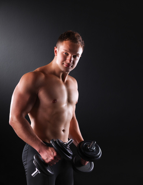 Handsome muscular man working out with dumbbells - Fotoğraf, Görsel