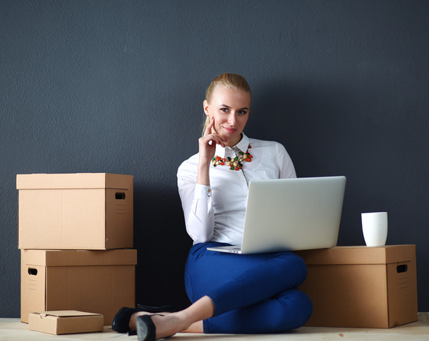 Woman sitting on the floor near a boxes  with laptop  - Foto, imagen