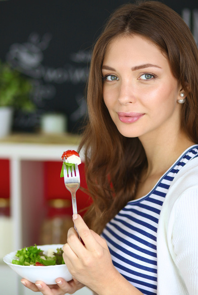 Young woman eating salad and holding a mixed salad  - Foto, Imagen