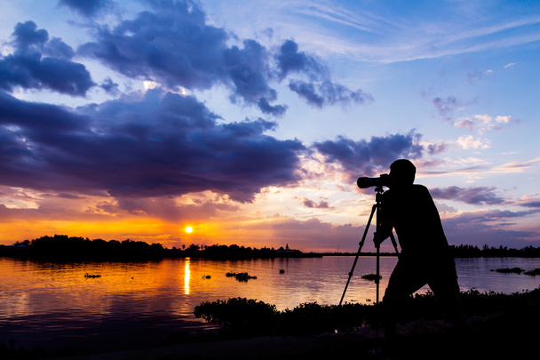 silhouette of photographer taking photo at sunset beside the riv - Foto, Imagen