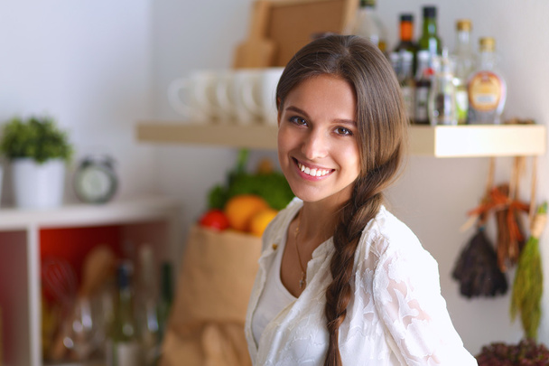 Young woman standing near desk in the kitchen - Foto, afbeelding