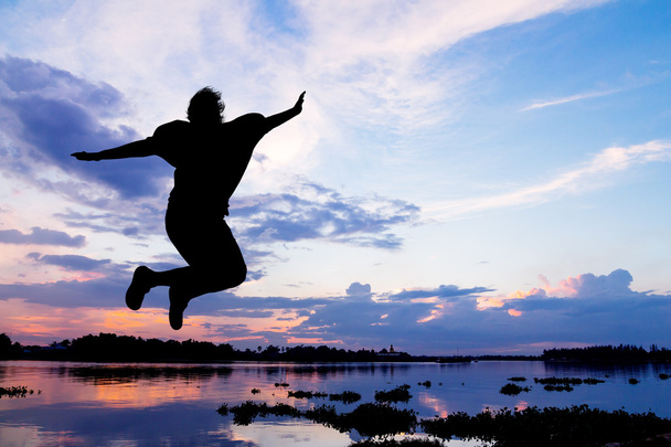 Дама, прыгающая счастливая у реки на закате
  - Фото, изображение