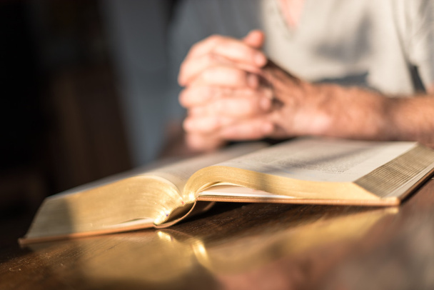 Man bidden handen op een Bijbel - Foto, afbeelding