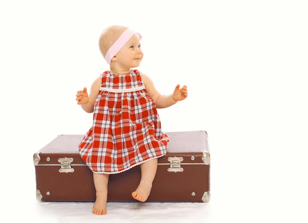 Happy child little girl in dress sitting on the suitcase playing - Photo, Image