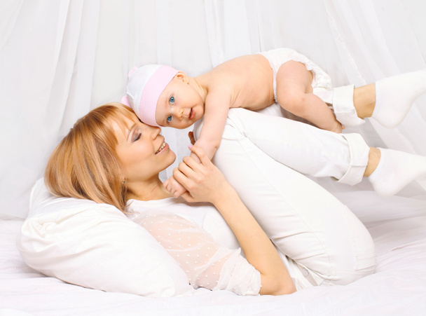 glückliche Mutter spielt Spaß mit Baby zusammen auf dem Bett bei - Foto, Bild