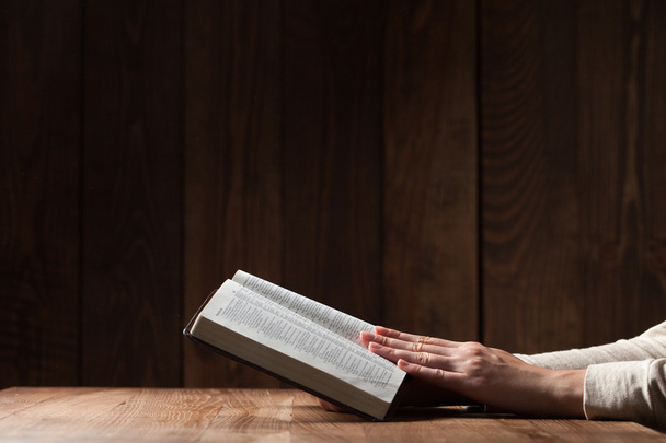woman reading the bible in the darkness over wooden table - Photo, Image