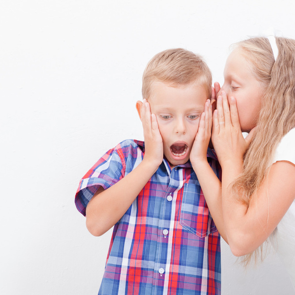Teenage girl whispering in the ear of a secret teen boys on white  background - Foto, Imagem