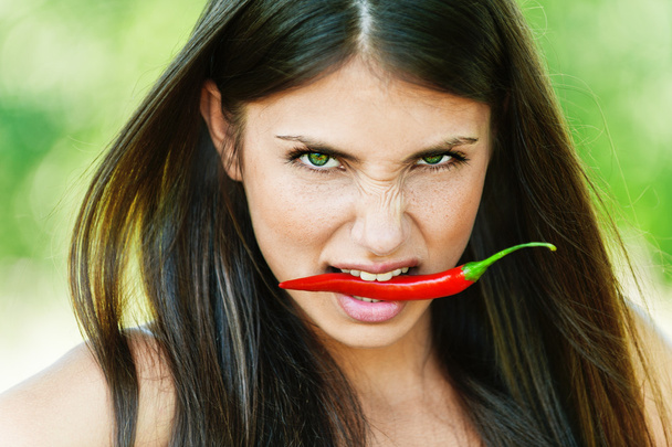 meisje met chili peper in tanden - Foto, afbeelding