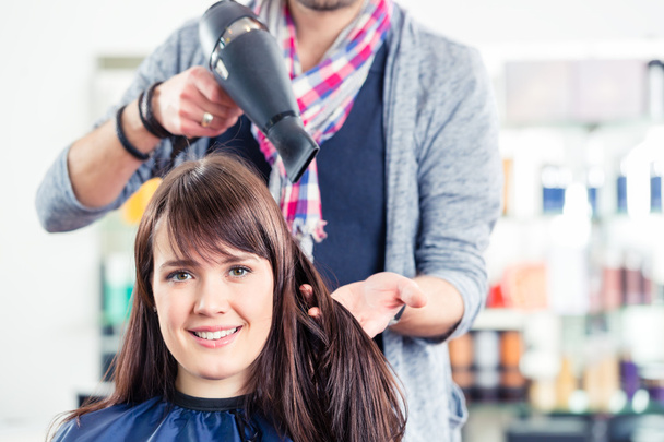 Hairdresser blow dry woman hair in shop - 写真・画像
