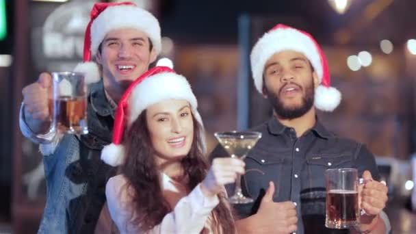 Três amigos alegres em chapéu de Santa com copos de cerveja sorrindo para a câmera
 - Filmagem, Vídeo