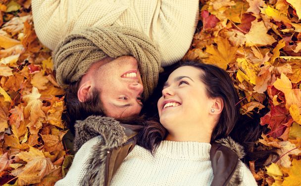 close up of smiling couple lying in autumn park - Valokuva, kuva