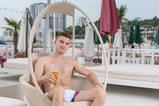 Young Man Relaxing on Deck with Glass of Beer - Fotó, kép