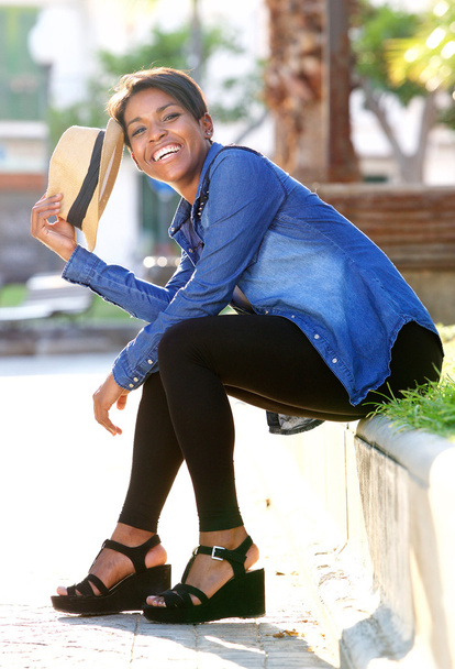 Glimlachen van jonge african american vrouw zitten buiten - Foto, afbeelding
