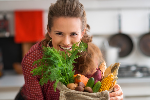 Smiling woman looking over a burlap sac of fresh fall vegetables - Foto, imagen