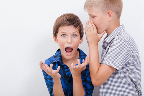 Teenage boy whispering in the ear a secret to friendl on white  background - Foto, Bild