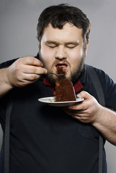 Funny fat guy eating chocolate cake - Foto, afbeelding