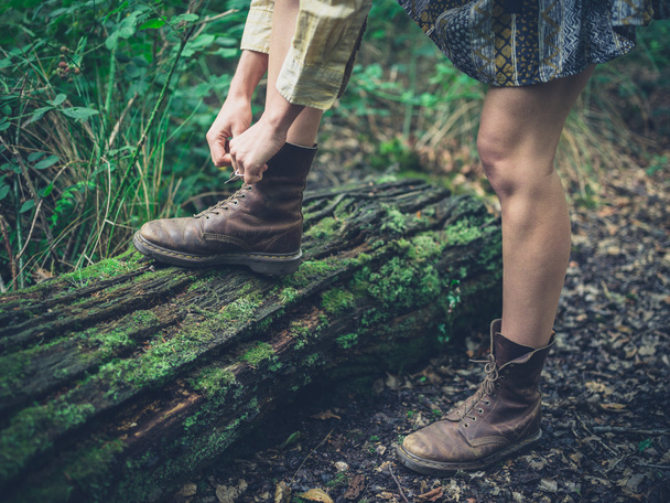 Mulher amarrando seus sapatos na floresta
 - Foto, Imagem