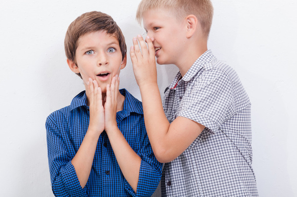 Teenage boy whispering in the ear a secret to friendl on white  background - Foto, Imagen