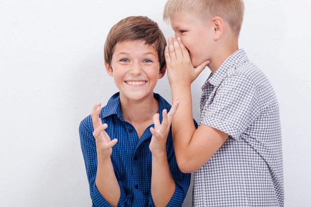 Teenage boy whispering in the ear a secret to friendl on white  background - Fotoğraf, Görsel