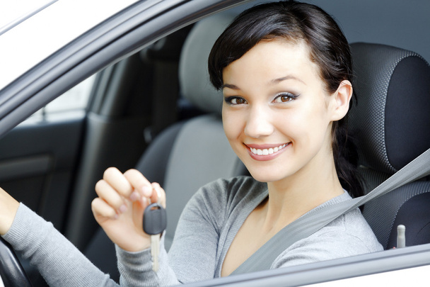 Досить жіночий водій у білому автомобілі, що показує ключ автомобіля
 - Фото, зображення