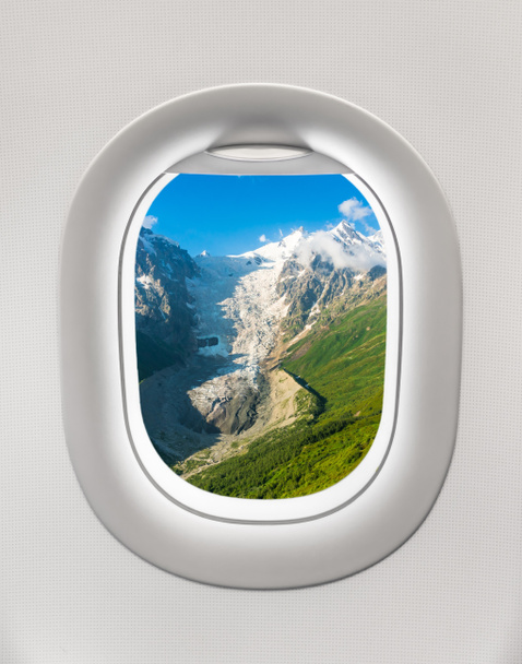 Κοιτώντας έξω από το παράθυρο του αεροπλάνου στα βουνά και στον παγετώνα - Φωτογραφία, εικόνα