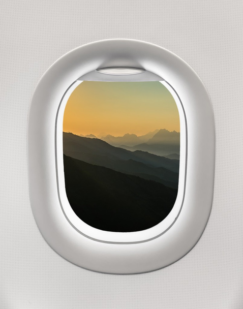 Mirando por la ventana de un avión a las montañas y al atardecer
 - Foto, imagen