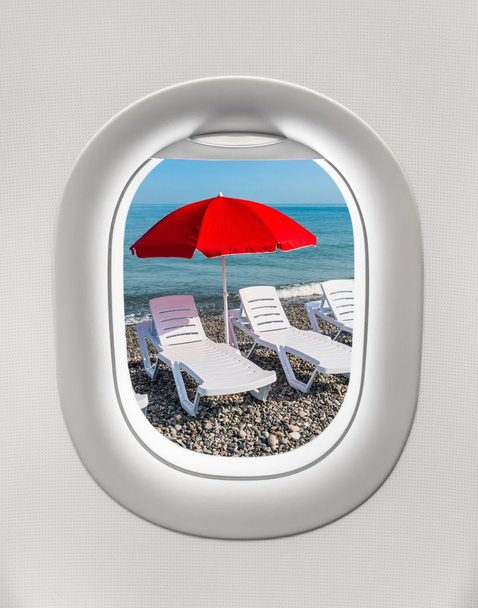 Κοιτώντας έξω από το παράθυρο του ένα αεροπλάνο για τις ξαπλώστρες και ομπρέλα - Φωτογραφία, εικόνα