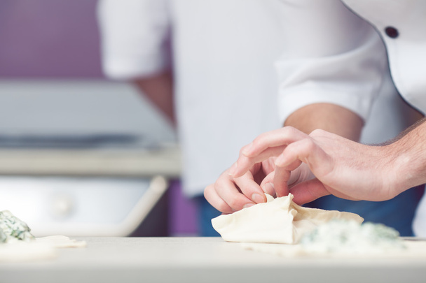 Vegetarian bakery concept. Cook's hands putting filler of spinach and feta - Foto, imagen