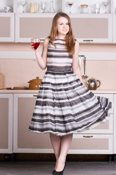 Houkutteleva nuori nainen mekko tilalla lasi viiniä hänen keittiö
. - Valokuva, kuva
