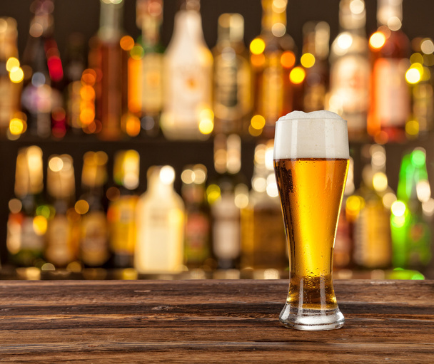Glass of light beer with bar on background - Photo, Image