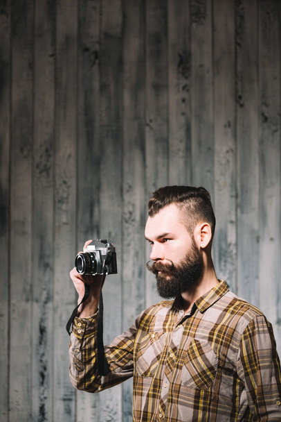 Γενειοφόρος άνδρας παίρνει φωτογραφία με vintage φιλμ φωτογραφικής μηχανής - Φωτογραφία, εικόνα