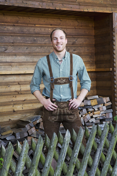 young man in bavarian lederhosen in front of firewood - Fotografie, Obrázek