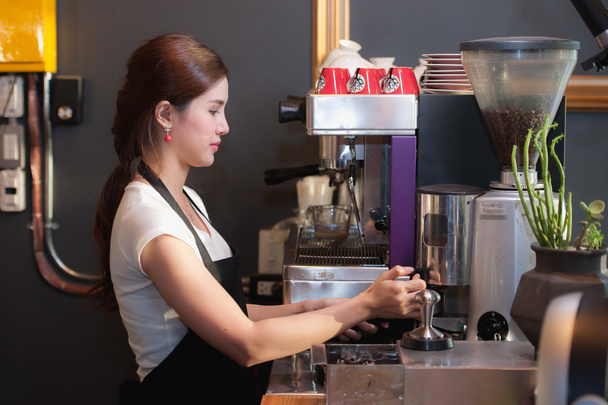 Жінка-бармен робить каву за допомогою кавоварки
. - Фото, зображення