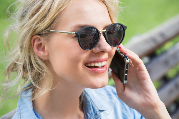 Cute blonde talking on a cell phone. - 写真・画像