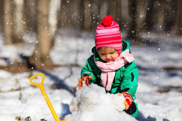 bambina che scava neve in inverno
 - Foto, immagini