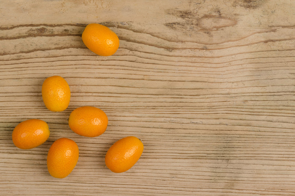 Kumquats ovalados en tablero de madera de abeto viejo
 - Foto, imagen