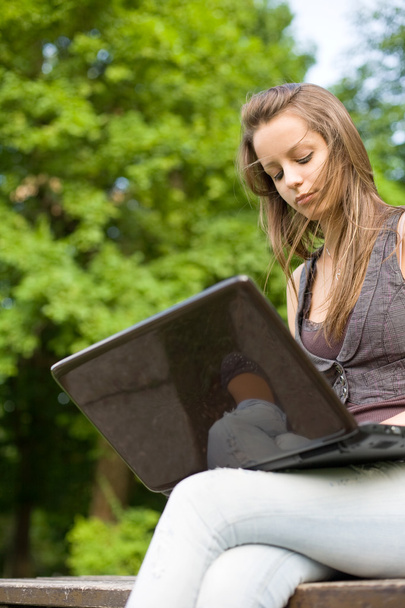 Young student with her laptop outdoors. - Фото, изображение
