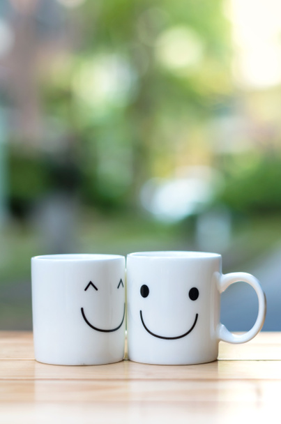 ボケ味は、愛の概念についての木製のテーブルの上の 2 つの幸せカップ - 写真・画像