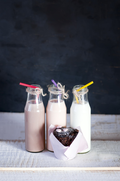 Three retro bottles with milk cocktail  and chocolate cupcake.  - Foto, Imagen