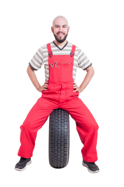 Happy mechanic sitting on car wheel - Photo, Image