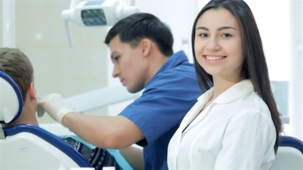 O dentista examina os dentes e a assistente sorri e levanta os polegares
 - Filmagem, Vídeo