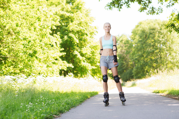 happy young woman in rollerblades riding outdoors - Zdjęcie, obraz