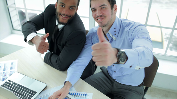 Два успішних бізнесмена посміхаються і показують великий палець вгору
 - Кадри, відео