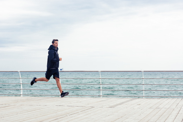 Sports man running near sea o - Foto, Bild