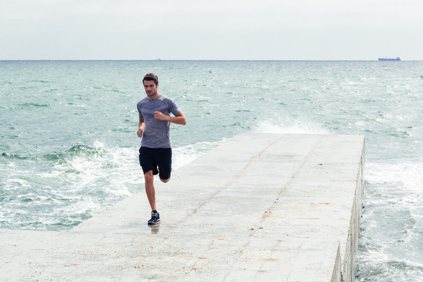 Чоловік біжить на пляжі на відкритому повітрі
 - Фото, зображення