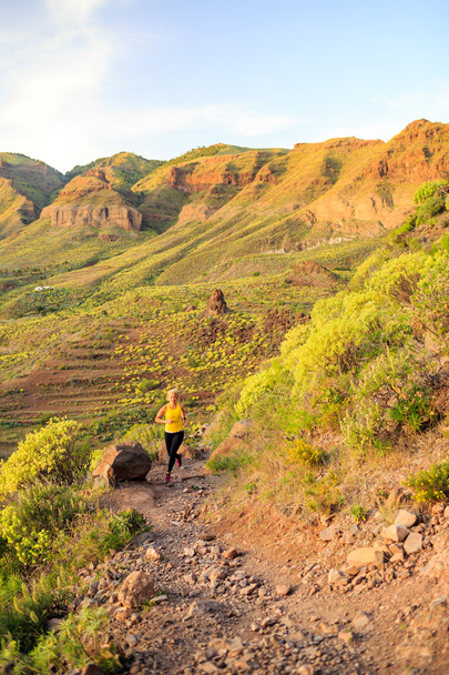 Mujer corriendo en las montañas rocosas en el atardecer de verano
 - Foto, Imagen