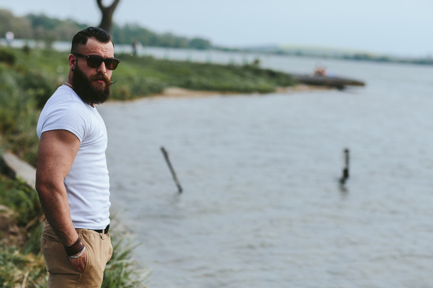 Amerikaanse bebaarde man kijkt op de rivier bank - Foto, afbeelding