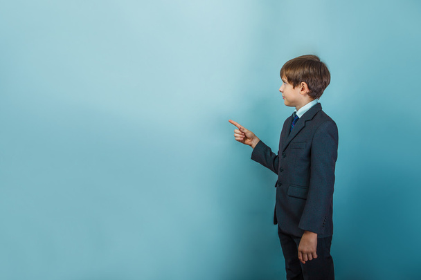 um menino de doze europeu aparência em um terno mostra seu dedo t
 - Foto, Imagem