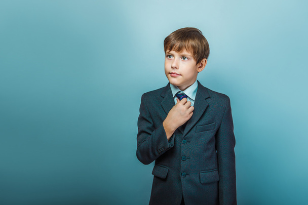 a boy of twelve European appearance in a suit straightens his ti - Fotografie, Obrázek