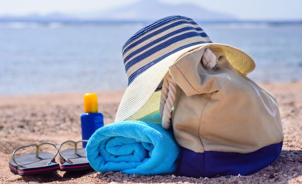 Borsa da spiaggia e cappello da sole sulla spiaggia soleggiata e deserta
 - Foto, immagini